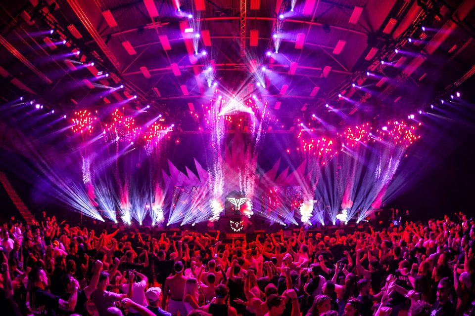 Confetti and pink beams over a packed dancefloor