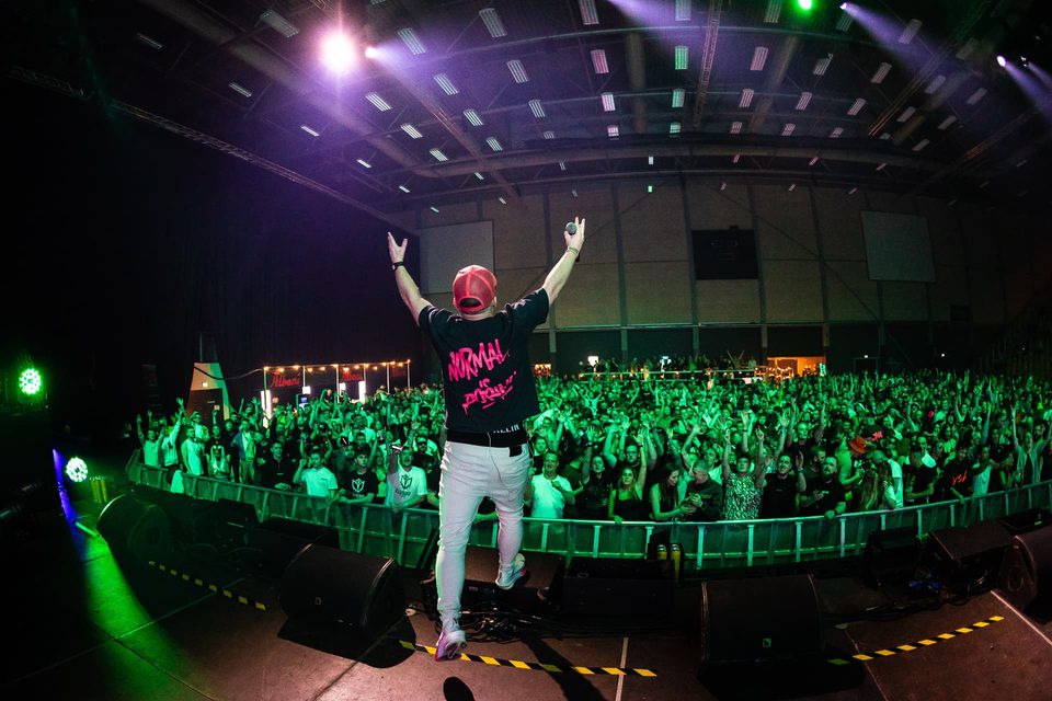 MC on stage facing the crowd in green light
